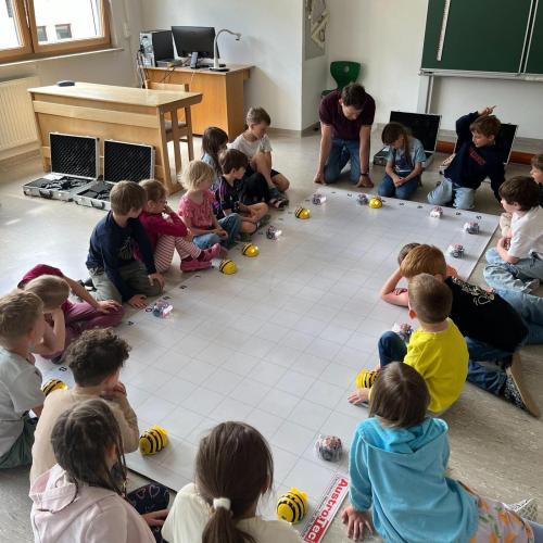 Kinder sitzen um Bee-Bot-Teppich