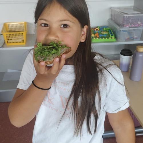 Kind beißt in Brot mit Belag aus dem Garten