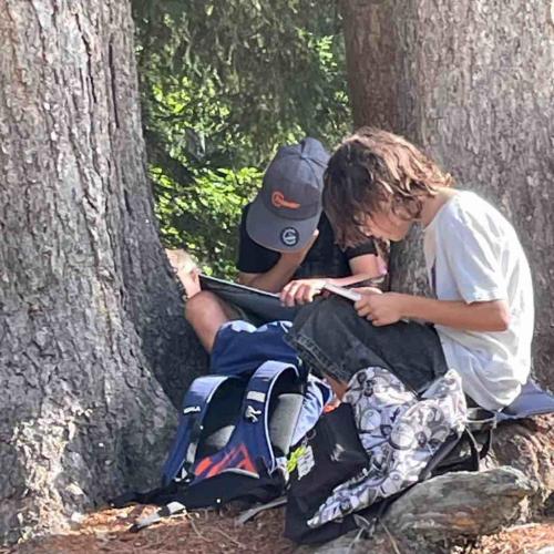 Kinder sitzen unter Baum und lesen