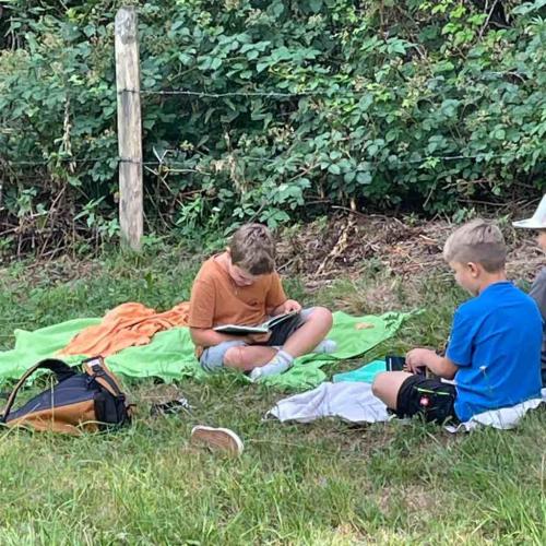 Kinder sitzen auf Decken und lesen