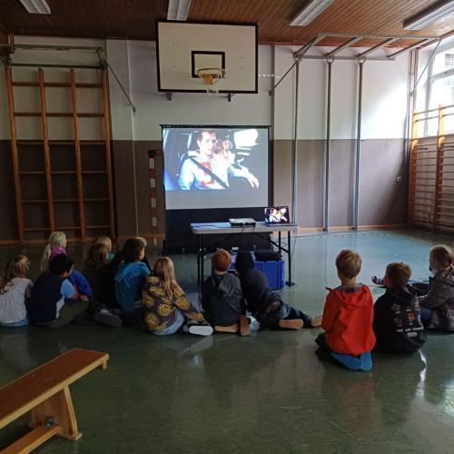 Kinder in Turnsaal vor Bildschirm