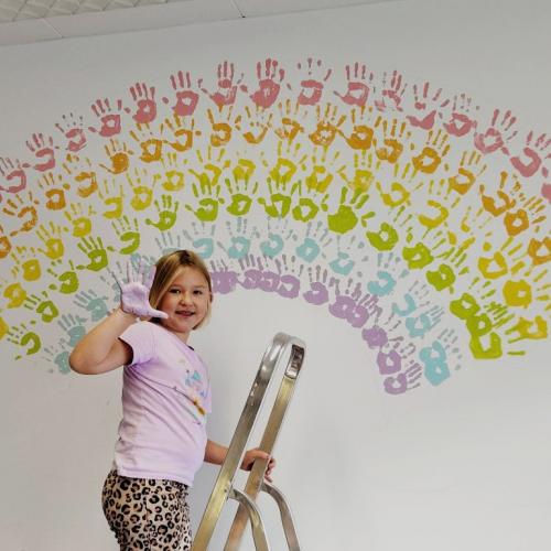 Kind auf Leiter mit bunter Hand