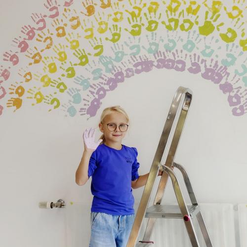 Kind auf Leiter mit bunter Hand