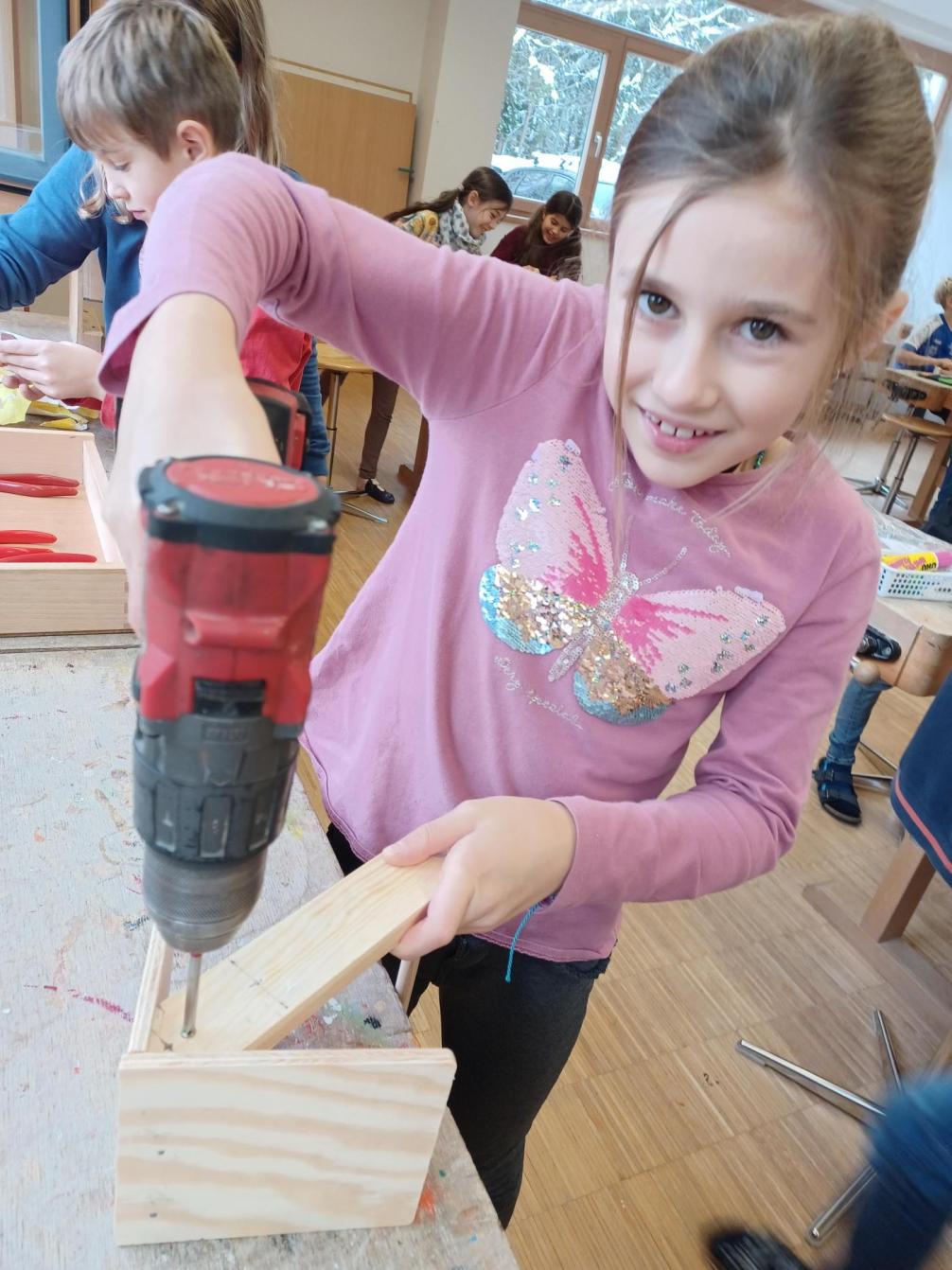 Eine Schülerin verschraubt die Holzteile mit einer Akkubohrmaschine. 