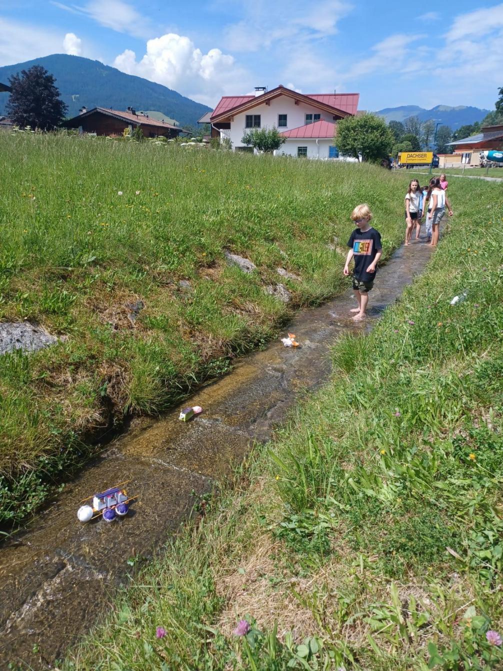 Kinder probieren ihre Boote im Bach aus. 