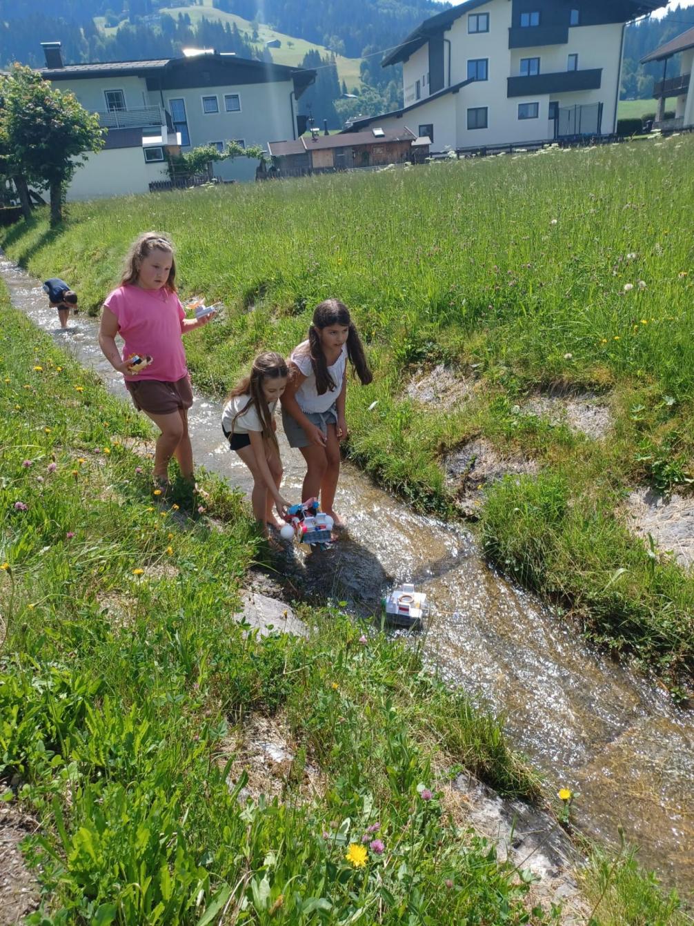 Kinder setzen ihre Boote in den Bach und hoffen, dass sie schwimmfähig sind. 